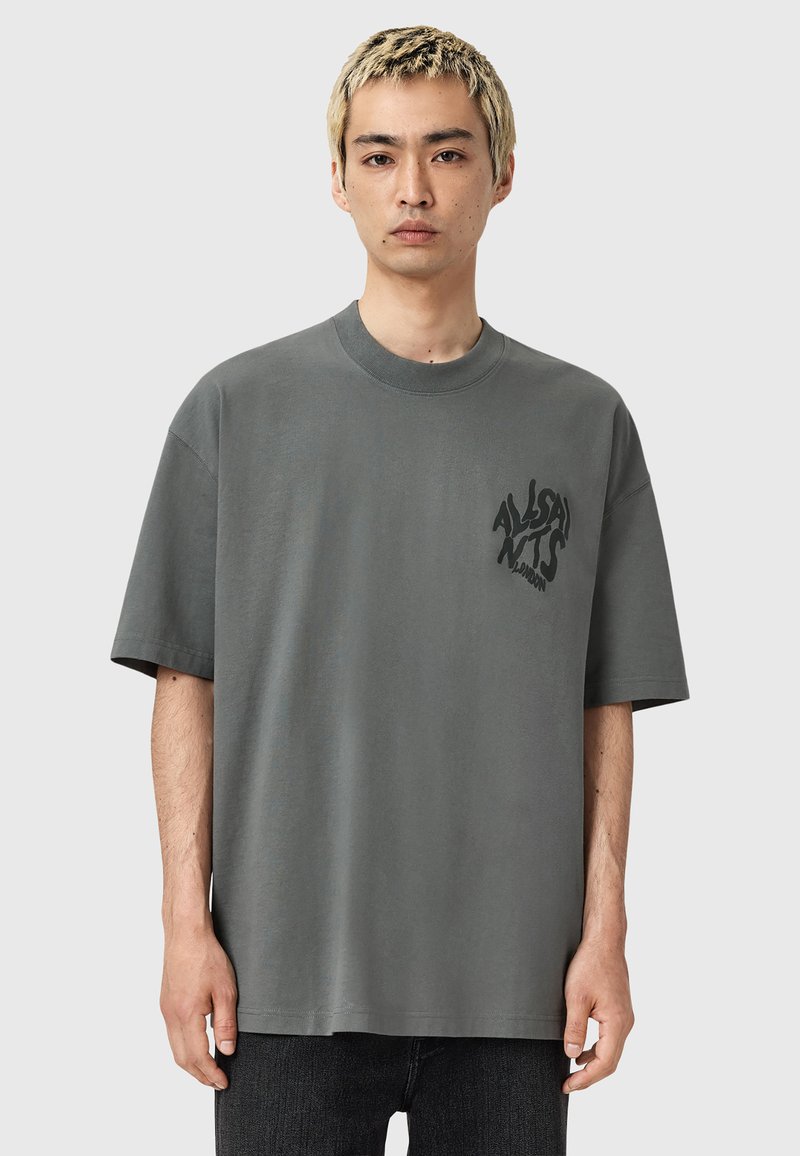 Szara koszulka z krótkim rękawem wykonana z bawełny, z okrągłym dekoltem i nadrukowanym logo na lewej stronie klatki piersiowej. Luźny krój.