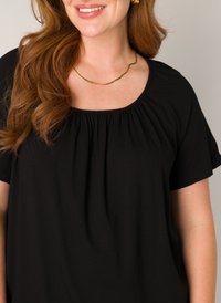 Zwarte top met korte mouwen en een ronde halslijn met geplooid detail. Gouden, golvende ketting accentueert de outfit. Soepele stofstructuur.