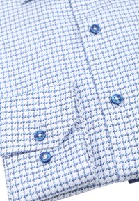 Blauw-wit gestreept shirt met een klein herringbone patroon, blauwe knopen en een linkse borstzak met knoopsluiting.