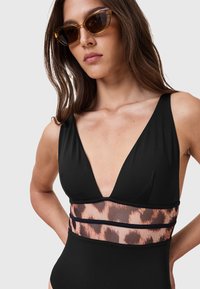 Sort one-piece badedragt med dyb V-hals, der har et leopardprint meshbånd i taljen. Glat stof med brede skulderstropper.