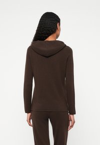 Bruine hooded long-sleeve top van zacht materiaal, met een ontspannen pasvorm en een eenvoudige halslijn met minimale stikdetails.
