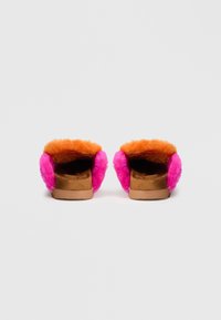 Chaussons marron à enfiler avec des dessus orange duveteux et des côtés rose vif, montrés de l'arrière sur un fond clair.