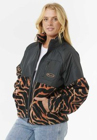 Chaqueta de forro polar con un patrón negro y naranja, cierre frontal con cremallera, cuello alto y bolsillo con cremallera en el pecho. Textura suave y corte holgado.
