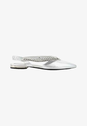 Chaussure plate argentée à bride arrière avec bout pointu, ornée d'une rangée de strass brillants le long de la bride.