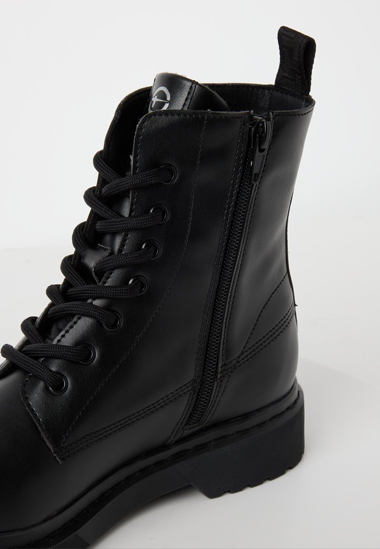 Bottine en cuir noir à lacets à l'avant, fermeture éclair sur le côté et semelle robuste. Présente une texture lisse et des accents de coutures contrastants.