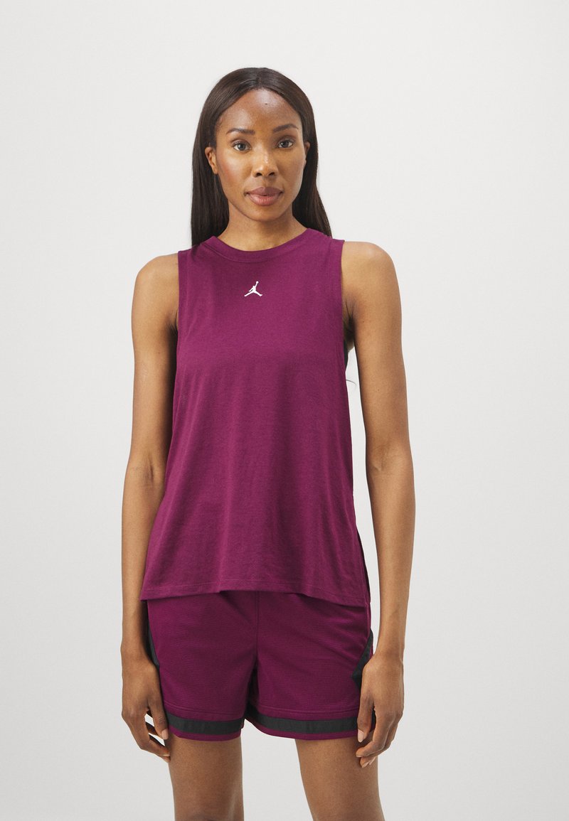 Bordeauxfarbener ärmelloser Sporttop mit Rundhalsausschnitt, versehen mit einem kleinen weißen Logo auf der Brust und einer lockeren Passform. Kombiniert mit passenden Shorts.