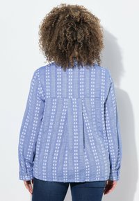 Camicia blu a motivi con maniche lunghe, caratterizzata da strisce orizzontali e motivi floreali. Tessuto morbido con una vestibilità rilassata.