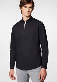 Czarna koszula z długim rękawem i zapięciem na guziki, wykonana z gładkiego materiału, z kołnierzykiem ze spiczastymi końcami, posiadająca zapięcie z przodu i czarne guziki.