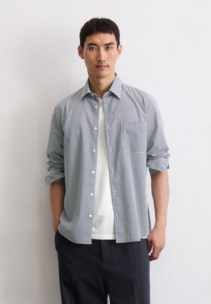 Button-up shirt with a black and white polka dot pattern, lightweight fabric, spread collar, long sleeves, and a single chest pocket.