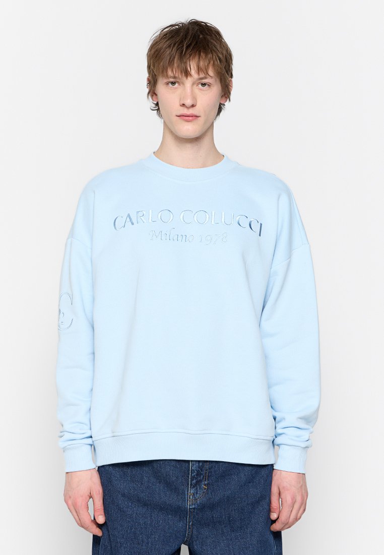 Lichtblauwe katoenen sweatshirt met geribde manchetten en onderkant, met reliëftekst "CARLO COLUCCI Milano 1978" op de voorkant en logo op de mouw.