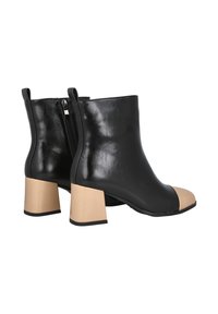Botas de tobillo de cuero negro con punta beige, con un acabado texturizado y un tacón cuadrado. Detalle de cremallera lateral para una fácil colocación.