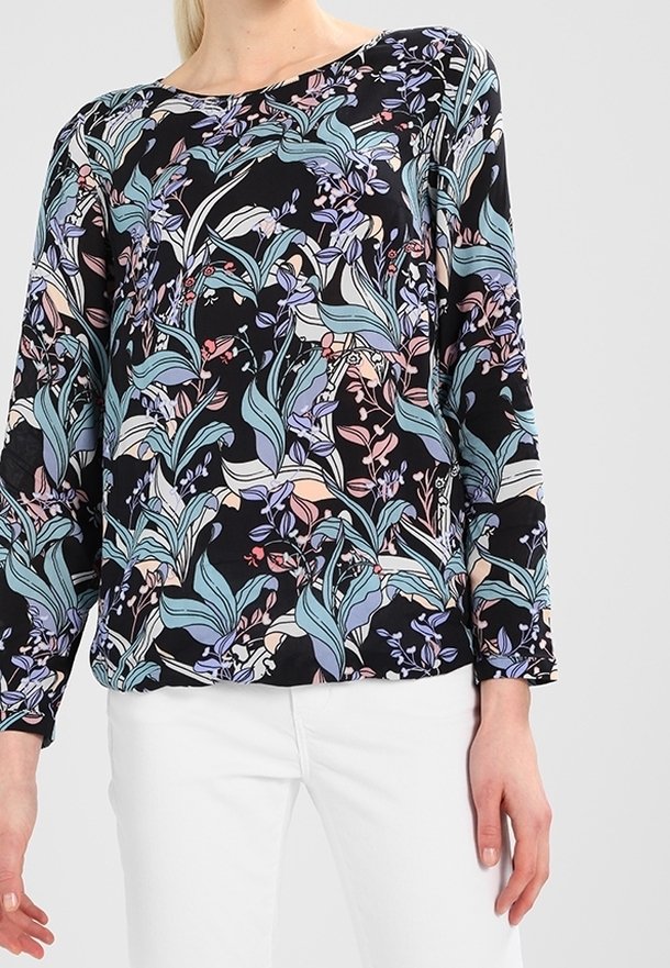 Blouse à manches longues avec une base noire ornée de motifs floraux vibrants dans des tons pastel, confectionnée en tissu léger et texturé.