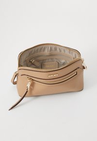 Borsa a tracolla in pelle tan con hardware in tono oro, dotata di scomparto principale con zip, tasca frontale e dettagli con logo.