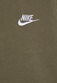 Tricou din bumbac de culoare verde olive, cu un logo Nike brodat alb în partea stângă sus. Textură netedă și design clasic cu gât rotund.