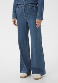 Blue wide-leg jeans made of denim, featuring a high waist, belt loops, and side pockets. Finished with a raw hem and subtle stitching details.