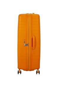 Valigia rigida arancione con scanalature verticali, due ruote scorrevoli, una maniglia laterale e una serratura a combinazione per la sicurezza.