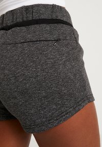Pantalones cortos texturizados en negro y gris con una cinturilla elástica y un pequeño bolsillo con cremallera en la parte posterior, diseñados para la comodidad y la movilidad.