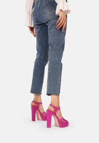 Sandali alti fucsia con plateau e cinturino alla caviglia, realizzati in suede e con design open-toe, visti da dietro.