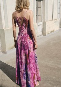 Langes Blumenkleid in Rosatönen und Lila. Mit tiefem V-Ausschnitt im Rücken und Bindedetails sowie einer fließenden Silhouette. Leichter Stoff.