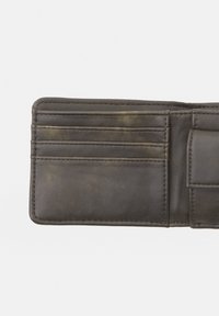 Intérieur de portefeuille en cuir marron foncé avec quatre emplacements pour cartes, un petit compartiment à billets et des zones texturées visibles.