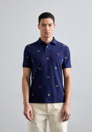 Laivaston polo-paita, jossa on monivärisiä brodeerattuja lippuja, klassinen kaulus ja lyhyet hihat, valmistettu pehmeästä puuvillamateriaalista.