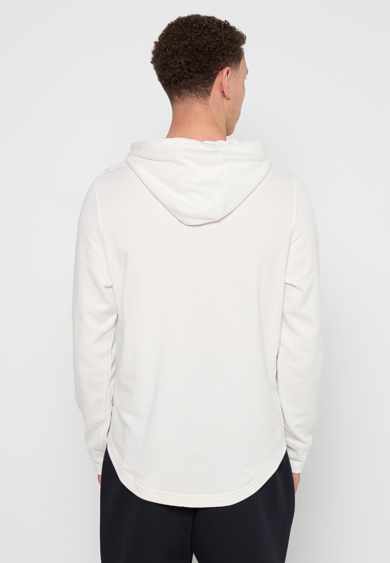 Sweat-shirt à capuche beige clair en tissu doux, présentant un ourlet arrondi, des manches longues et une couture au centre du dos.