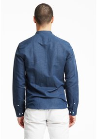 Marineblauwe lange mouw overhemd met een button-down kraag, gestructureerde stof, zichtbare naaddetails en witte knopen bij de mouwen en kraag.