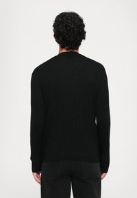 Schwarzer Strickpullover mit einem strukturierten Rautenmuster, rundem Ausschnitt und langen Ärmeln. Einfaches Design, keine sichtbaren Markenlogos oder Beschläge.