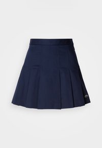 Mørkeblå plissert skjørt med en tettsittende midje, laget av et glatt stoff. Har en liten Lacoste-logo på sømmen.