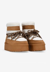 Botas de plataforma de ante marrón con acentos de piel de oveja blanca, que presentan un diseño de cordones y suelas de goma texturizadas para mayor agarre.