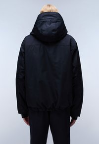 Chaqueta acolchada negra con una gran capucha, cinturilla elástica y textura suave. Diseñada para proporcionar calidez, presenta un diseño minimalista y sin cierres visibles.