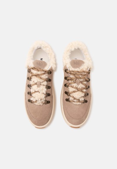 Paire de baskets en daim beige avec une doublure blanche duveteuse et des lacets assortis, vues de dessus sur un fond clair.