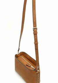 Brązowa torebka typu crossbody o teksturze z regulowanym paskiem, zamknięciem na zamek błyskawiczny oraz srebrnymi akcentami. Gładkie wykończenie wnętrza.