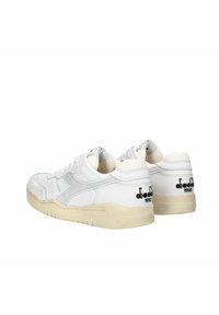 Scarpe da ginnastica bianche con accenti grigi, tessuto testurizzato e pelle liscia. Presentano una suola beige e dettagli del logo ricamati.