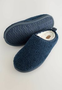 Marina blåtofflor med en fluffig yta, mjukt foder och gummisula. Har en ögla baktill för enkel på- och avtagning.