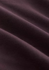Textiel in een rijke paarse kleur, met een glad, licht textuur oppervlak met fijne ribbels, dat een gedrapeerd, zachte uitstraling toont.