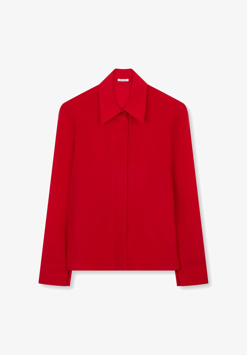 Chemise rouge à manches longues avec col pointu et patte de boutonnage dissimulée, présentée à plat sur un fond blanc.