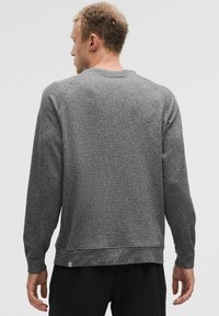 Pelēka teksturēta džemperis ar apaļu kaklu un garām piedurknēm. Ar ribotu apakšmalu un piedurknēm, minimāla zīmola atzīme kreisajā apakšējā stūrī.