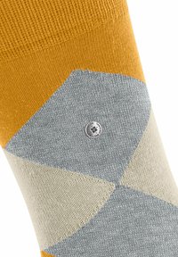 Calzino giallo e grigio con motivo a forme geometiche e un piccolo logo circolare, che mette in evidenza la sua texture e i dettagli del design.