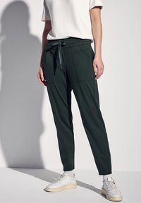 Mörkgröna joggerbyxor i mjukt tyg, med elastisk midja och dragsko, sidofickor och tapered ben-design.