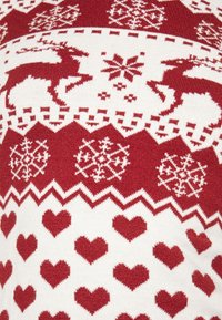 Rood-wit gebreide trui met een herhalend patroon van rendieren, sneeuwvlokken en harten. Gestructureerde stof met feestelijke motieven.