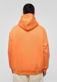 Oversized oranje sweatshirt met een capuchon, met een gladde textuur en geribbelde manchetten. De zoom is elastisch, wat zorgt voor een ontspannen pasvorm.