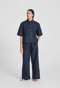Camicia azzurra marina a maniche corte con bottone e pantaloni a gamba larga coordinati, realizzati in tessuto leggero con una consistenza liscia.