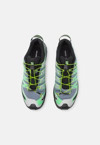 Trail running sko med en grå mesh-overdel og limegrønne accenter, sort foring og et hurtigt snøresystem. Struktureret overflade og robust sål.