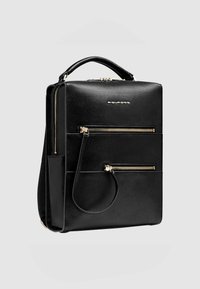 Mochila de cuero negro con forma rectangular, que cuenta con dos bolsillos frontales con cremallera, una asa superior y detalles en hardware dorado.