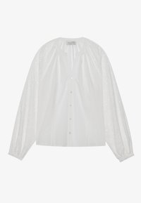 White blouse with button front, featuring sheer puff sleeves adorned with a subtle dotted pattern and gathered cuffs. Soft fabric texture.
