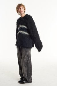 Black, fluffy knit sweater with white and blue horizontal stripes, paired with loose gray pants and black shoes with white accents.