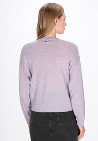 Laza szabású, hosszú ujjú, bordázott szélű lila kötött pulóver, amely finom textúrával és egy kis márkajellel rendelkezik a hátsó részén.
