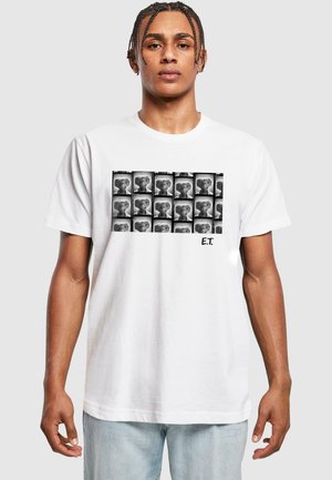 Hvid bomulds-T-shirt med et sort-hvidt grafik af E.T. i et gittermønster; teksten "E.T." trykt i nederste højre hjørne.