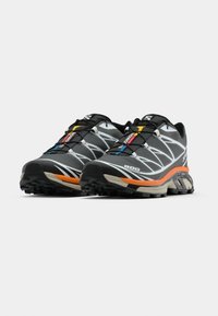 Μαύρα και γκρι παπούτσια για τρέξιμο σε μονοπάτια με αντανακλαστικές λεπτομ έρειες, υφασμένες σόλες, πολύχρωμα κορδόνια και επενδυμένη φτέρνα για ανθεκτικότητα.